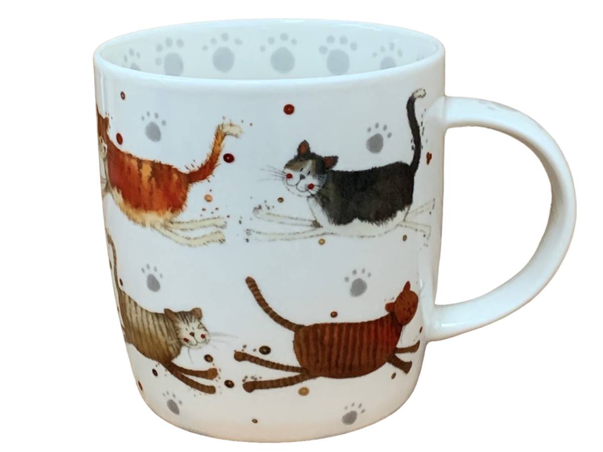 A white ceramic mug decorated with illustrations of four playful cats in various colors, interspersed with gray paw prints and small brown speckles, shown against a plain white background.