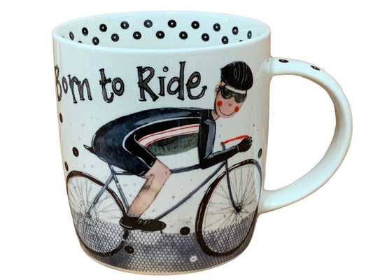 A white ceramic mug featuring a vintage-style illustration of a cyclist riding a bicycle, with the text 'Born to Ride' printed on the side. The mug is decorated with black polka dots and has a black-and-white bicycle graphic at the bottom.