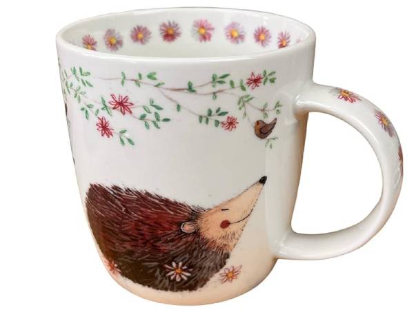 A white ceramic mug decorated with a brown hedgehog illustration, green leaves, red flowers, and a small bird, shown on a plain white background.