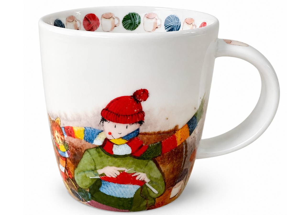 A white ceramic mug featuring a whimsical illustration of a child knitting in the winter, with a colorful pattern of knitted balls of yarn decorating the inner rim.