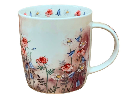 A white ceramic mug decorated with a watercolor-style floral pattern featuring red roses, blue bellflowers, and white daisies on a soft pink and brown background, shown against a plain white background.