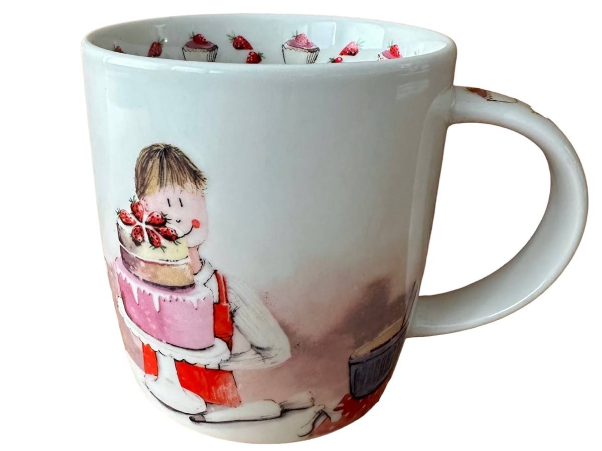 A white ceramic mug featuring a whimsical illustration of a child holding a strawberry-topped cake, with a matching pattern of cupcakes printed around the inside rim.
