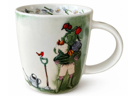 A white ceramic mug featuring a whimsical illustration of a gardener carrying vegetables, with a small red bird, watering can, and gardening tools on a white background.