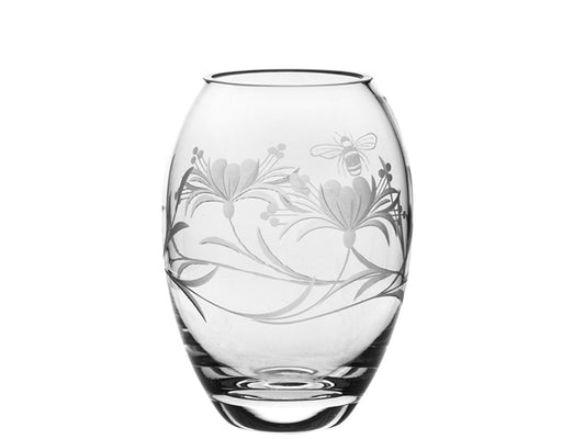 This Royal Scot Crystal Bee & Honeysuckle Small Barrel Vase is ideal for displaying short-stemmed flowers in your home. It has been hand-cut in Britain with delicate honeysuckle flowers around its exterior, along with a bumblebee flying amongst them. The vase is tapered and rounded, and has a thick crystal base.
