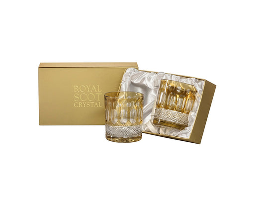A pair of amber and clear tumblers with a relief pattern cut into the outside. They come in a gold presentation box with a white silk lining.