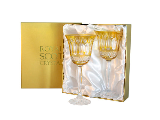 A pair of amber and clear crystal wine glasses with a relief pattern cut into the outside. They come in a gold presentation box with a white silk lining.