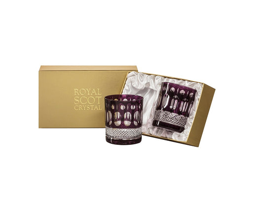 A pair of purple and clear crystal tumblers with a relief pattern cut into the outside. They come in a gold presentation box that is lined with white silk