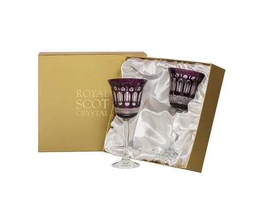 A pair of purple and clear wine glasses with art-deco style panels cut into the exterior. They come in a gold presentation box that is lined with white silk