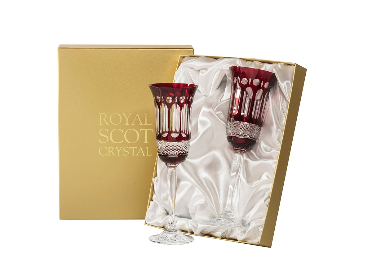 A pair of red and clear crystal champagne flutes with panels cut into the exterior to show the opposite colour. They come in a gold and white silk-lined presentation box.