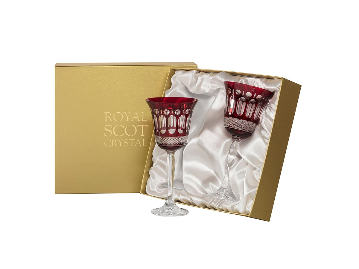A pair of large wine glasses with ruby bowls and a flared lip, coloured a vibrant ruby shade with clear panels cut into the outside
