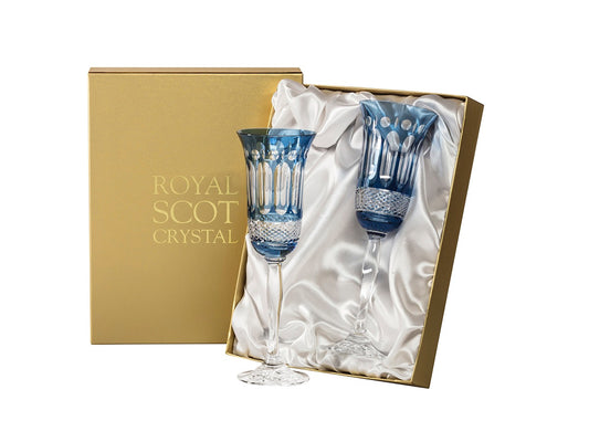 A pair of blue and clear crystal champagne flutes with a relief pattern cut into the outside. They come in a gold presentation box with a white silk lining.