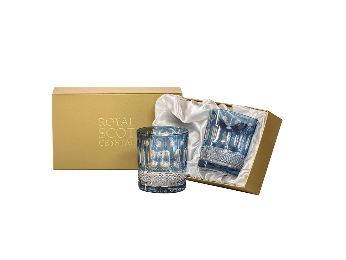 A pair of blue and clear crystal tumblers with a relief pattern cut into the outside. They come in a gold presentation box with a white silk lining.