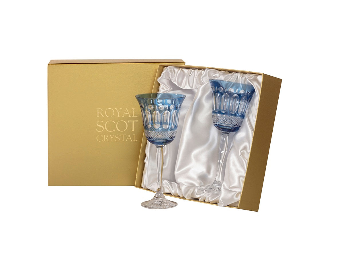 A pair of sky blue wine glasses with a cut design that reveals clear panels and a clear stem. They come in a gold presentation box that is lined with white silk