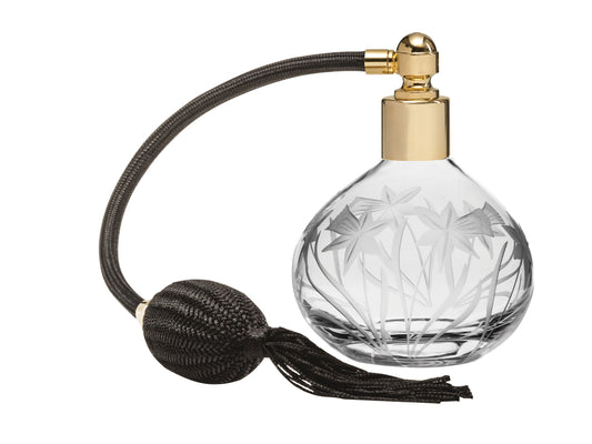 A crystal bottled perfume atomiser with daffodils cut into the outside, with a gold top and black puffer