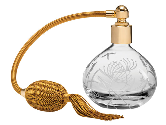 A crystal perfume atomiser bottle with dragonflies and delicate botanicals carved into the outside, topped with gold hardware and a gold puffer