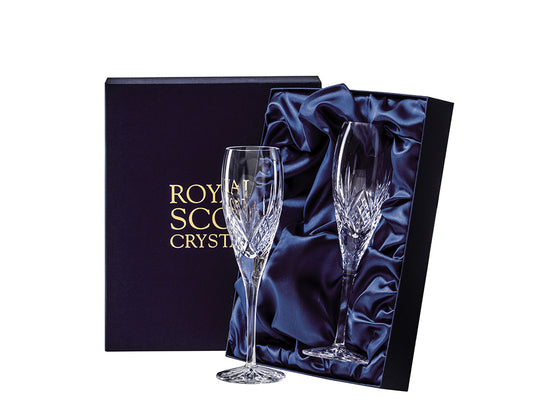 A pair of crystal champagne flutes in a navy blue silk-lined presentation box. The flutes are hand-cut with a bed of diamonds just above the stem and a five-pointed fan reaching towards the smooth rim