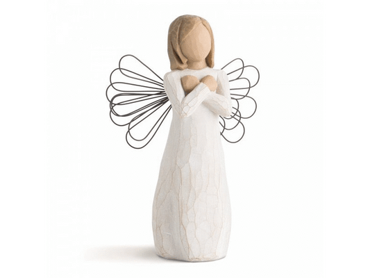 A faceless angel figurine with detailed wire wings and a white gown stands with crossed arms, closed fists, a sign for Love. She is painted in a muted colour palette of soft, earthy tones.