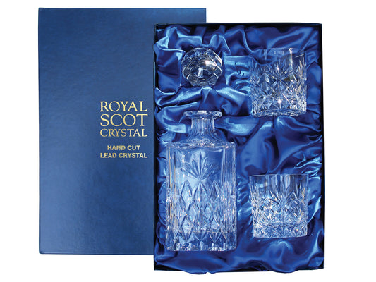 A decanter and pair of matching whisky glasses with a kintyre design on them. There is a bed of diamonds around the base of each piece, topped with a seven-pointed fan. They have smooth tops, and the decanter has a golf-ball style stopper. They come in a navy-blue silk-lined presentation box with gold branding on the lid.
