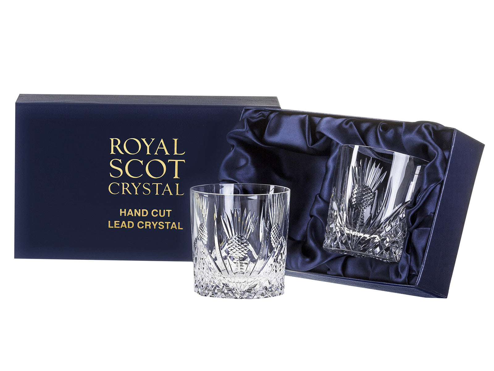 A pair of straight-edged crystal tumblers with a scottish thistle pattern cut into the exterior. They come in a navy-blue silk-lined presentation box with gold branding on the lid.