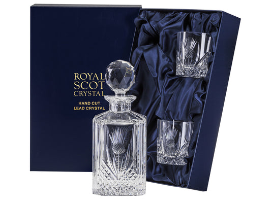 A crystal decanter with two matching whisky glasses, all cut with a bed of diamonds around the base with a scottish thistle cut into each side, with smooth tops. The decanter has a golf-ball style stopper. They come in a navy-blue silk-lined presentation box with gold branding on the lid.