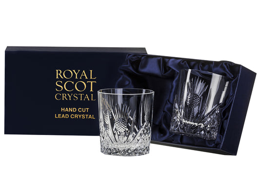 A pair of straight-edged crystal glasses with a scottish thistle designcut into the exterior. They come in a navy-blue silk-lined presentation box