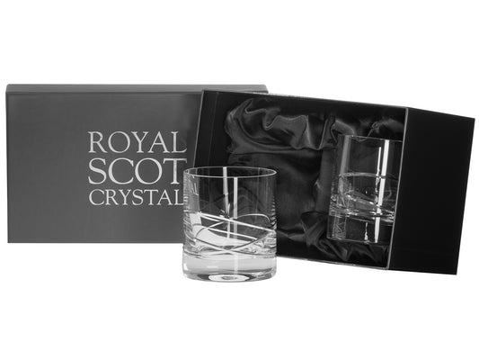A pair of large crystal tumblers with a sweeping orbital design cut around the outside of the base. They come in a slate-grey silk-lined presentation box with silver branding on the lid.