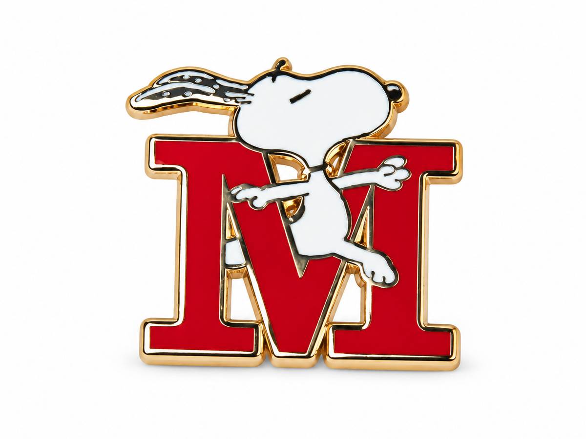 A Snoopy enamel pin featuring the character standing on a large red letter M with gold-tone metal outlines, shown on a plain white background.