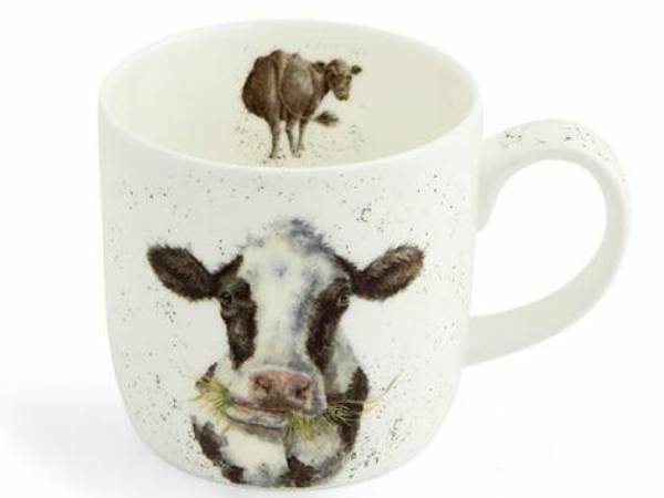 A speckled white ceramic mug featuring a realistic black-and-white cow illustration on the front and a smaller cow scene printed inside the cup.